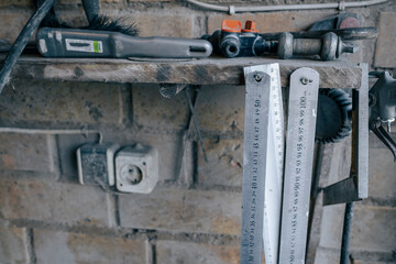 brick wall in workshop some tools on shelf. Metal rulers ganging.