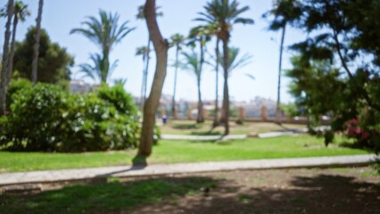 Fototapeta premium Blurred park scene with out-of-focus palm trees under a sunny sky, highlighting a serene, idyllic outdoor environment on a bright day