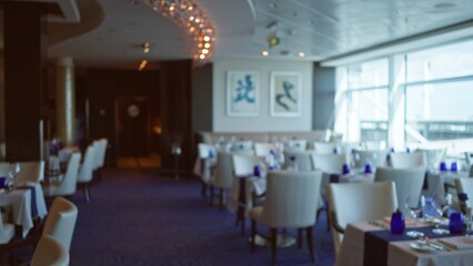 Indoor view of a luxury restaurant with blurred background, showcasing elegant decor, defocused tables, serene ambiance, and modern bokeh lighting.