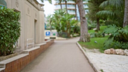 Blurred street scene in monaco with luxury surroundings, showcasing a defocused, bokeh-rich outdoor environment with lush greenery and architectural elements.