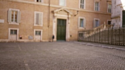 Blurred scene captures old street in rome with architectural background and cobblestone pavement, showcasing defocused historic buildings in an outdoor setting.