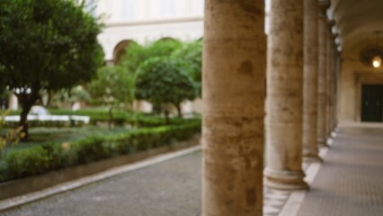Fototapeta premium Blurred stone columns and lush greenery at an old university campus create a peaceful, defocused outdoor scene with historical charm.