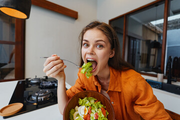 Young woman enjoying a fresh salad in a modern kitchen, showcasing healthy eating habits and vibrant colors in a bright, inviting space