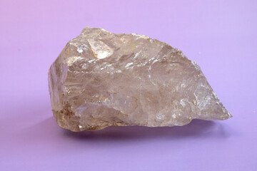 macro photography geological collection - raw clear quartz rock crystal stone on light purple background