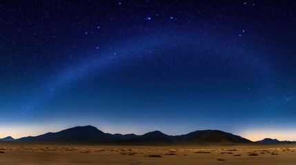 Starry night sky over vast desert landscape. Dark mountains silhouette against the night sky. Desert terrain stretches into the distance. Nighttime scene. Scenic outdoor view.