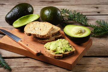 Delicious avocado toast with fresh avocados on wooden board