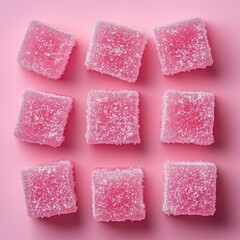 Top view of nine pink sugar-coated square jelly candies arranged in a 3x3 grid on a soft pink background.