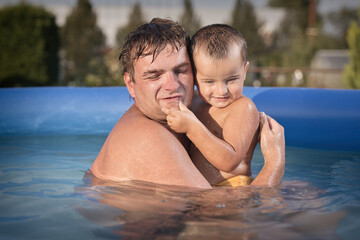 Couple of man and baby cooling during hot day in swimming pool on garden