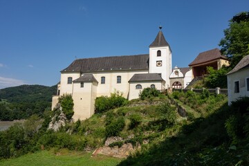 Fototapeta premium Ancient clock tower of Pfarre Schonbuhel church in Austria, EU with Danube