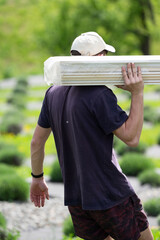 A male worker carries boards for sheathing a gazebo in a lavender field.