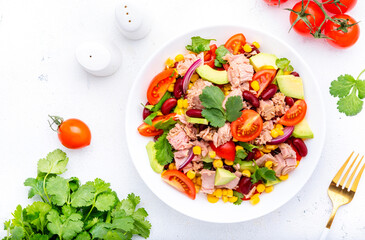 Mexican style salad with tuna, avocado, corn, beans, tomatoes and cilantro, white background, top view