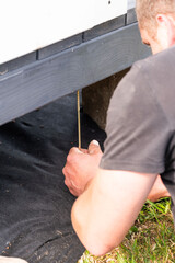 Installation work of a wooden gazebo, the master is screwing screws into the wooden floor.