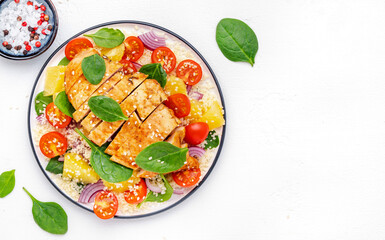 Nourishing salad with grilled chicken, couscous, tomatoes, onion, spinach and orange. White background, top view