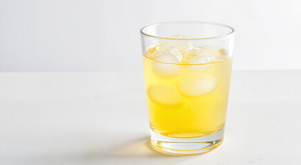 Refreshing iced citrus drink with ice cubes in a clear glass on a white background with copy space
