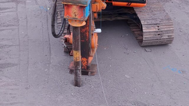Driving rig piler machine pushing steel tubular pile deep into ground as part of foundation works