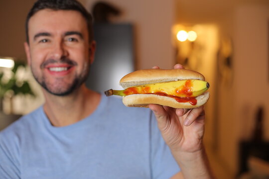 Man eating a hot dog with a raw banana instead of a sausage 