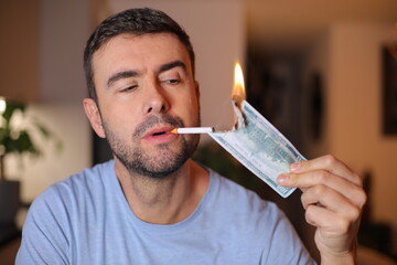 Man burning one hundred dollars to light his cigarette