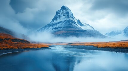 Fototapeta premium Majestic mountain landscape with a serene river flowing through a misty valley under a cloudy sky