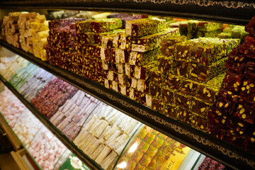 Pistachio and rose flavored turkish delight lokum arranged in rows behind the glass display of a...