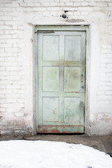 Weathered Green Wooden Door Against an Aged White Brick Wall