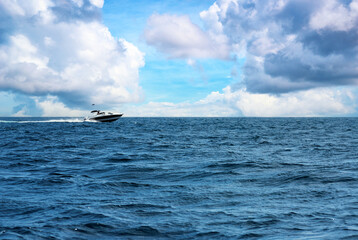 Luxury Speedboat Gliding on Open Ocean Under Vibrant Cloudy Sky
