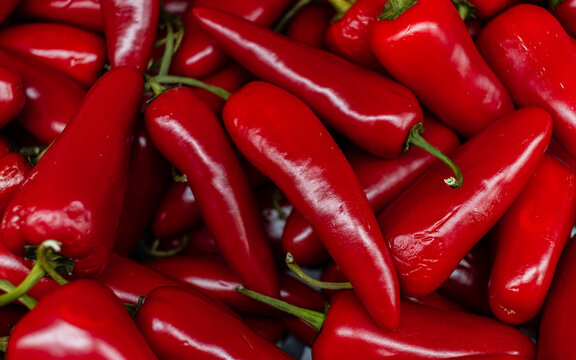 A vibrant close-up of fresh red chili peppers with green stems, showcasing their glossy texture and bold color, ideal for food and spice photography.