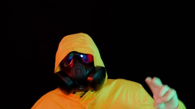 Cyberpunk dancer in hazmat suit performing in neon lights. Futuristic character in protective mask making peace sign on dark background - Powered by Adobe