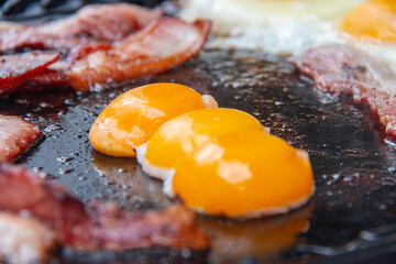 Cooked breakfast on a barbeque hot plate closeup with eggs and bacon