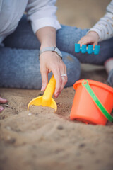 Mother and child playing together in sandpit. Woman playing with little daughter on playground outdoors. Childhood and parenthood concept