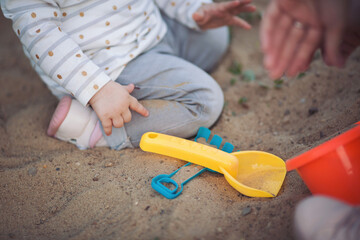 Mother and child playing together in sandpit. Woman playing with little daughter on playground outdoors. Childhood and parenthood concept
