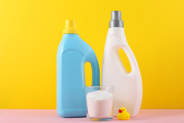 Detergents for washing children's clothes and children's clothes on a bright background