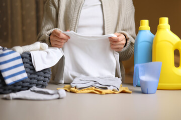 A woman folds baby things after washing. Detergents for washing children's clothes