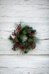 Authentic, beautiful Christmas Wreath with red decorative Ornaments on a rustic white Wall; Copy Space