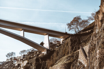 Ponte do Infante Bridge spans a rocky hillside with terraced walls and scattered trees in Porto,...