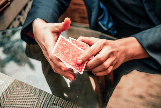 Magician show card trick, man play casino gambling, close up hands holding deck