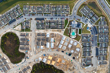 Aerial view of unfinished wooden frames of affordable houses under construction. Development of...