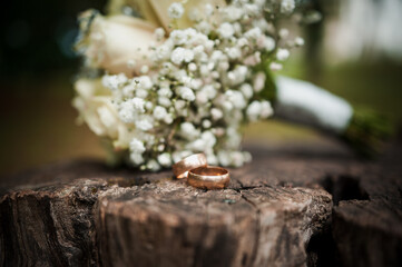 Romantic Wedding Rings and Beautiful Bouquet on Rustic Wood