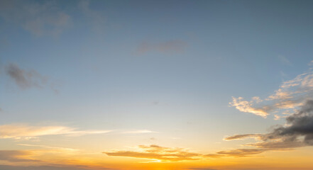 Colorful sunset sky with setting sun behind vivid orange and yellow clouds