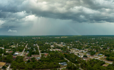 Obraz premium Dark stormy clouds forming on gloomy sky before heavy rainfall over suburban town area