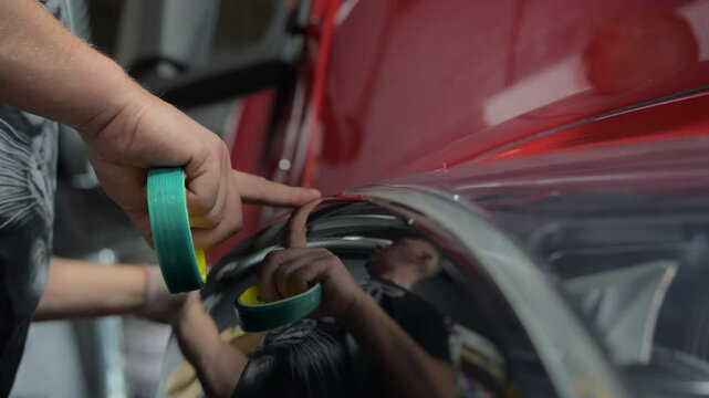 Process of applying a PPF film to a truck using a tape. Close up footage of applying a film on a truck. Close up