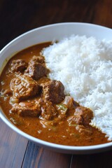 Beef curry with rice in a white bowl.