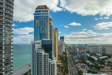 Obraz premium Sunny Isles Beach city with heavy urban traffic and expensive highrise hotels and condo buildings on Atlantic ocean shore. American tourism infrastructure in coastal southern Florida