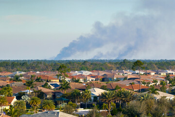 Fototapeta premium Toxic smoke from prescribed forest fire rising up over suburban neighborhood in Florida polluting air