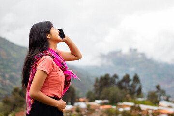 Mujer campesina atractiva en América Latina, feliz mientras usa un teléfono inteligente mirada a...