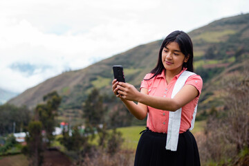 Mujer campesina atractiva en América Latina, feliz mientras usa un teléfono inteligente mirada a un espacio publicidad y aislada en un fondo naturaleza,contactar,celular,quechua