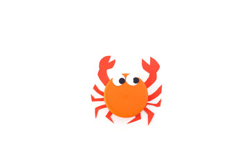 simple crab craft from plastic cap or lid and paper, kindergarten or school creative craft project, Orange plastic bottle cap transformed into crab toy. Minimalist flat lay composition, white