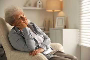 Loneliness concept. Sad senior woman sitting in armchair at home