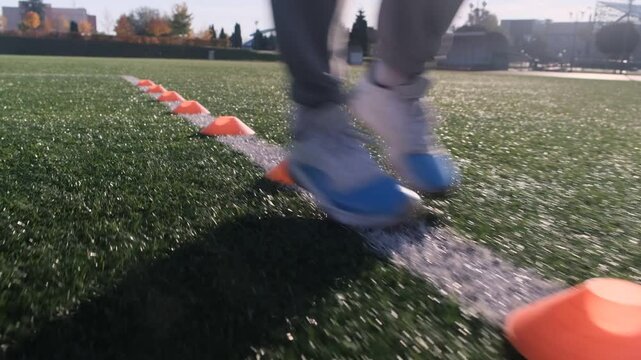 An athlete&rsquo;s feet near training cones on a sports field. It is daytime and sunny