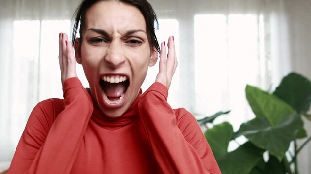 Young woman expressing intense frustration while screaming in slow motion