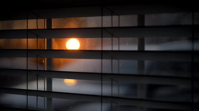 Looking at sunset through window closed by blinds. Close up shot